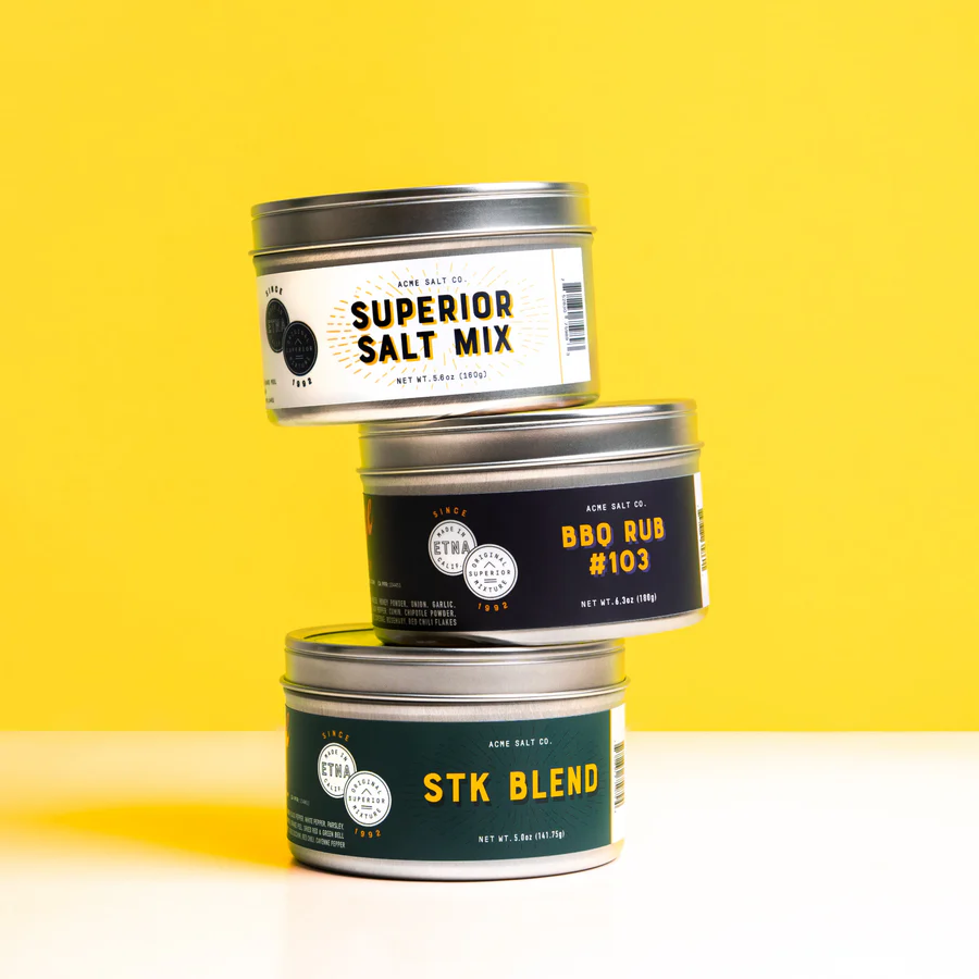 Eight shirts arranged on table in black, olive, grey, blue, white, red, mustard, and green.